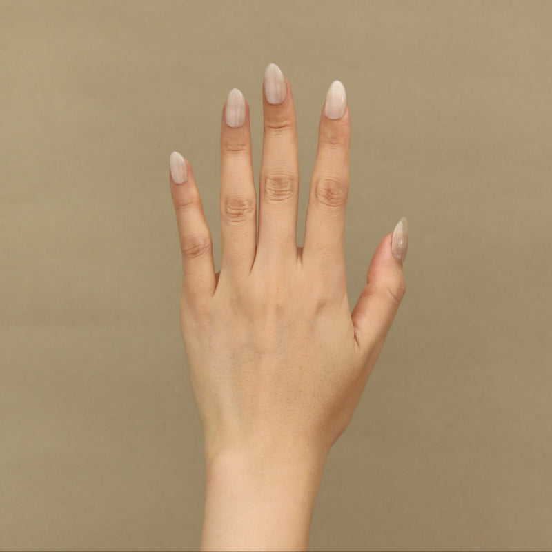 Hand with light nail polish on a beige background