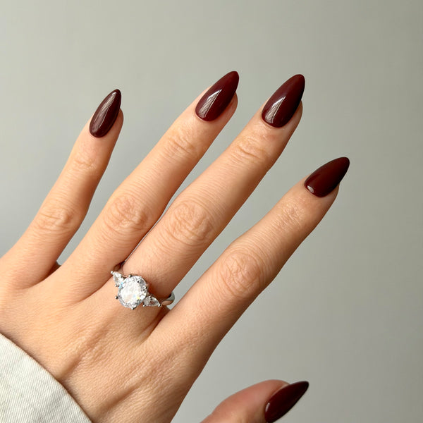 glossy burgundy almond press-on nails on hand with minimal look
